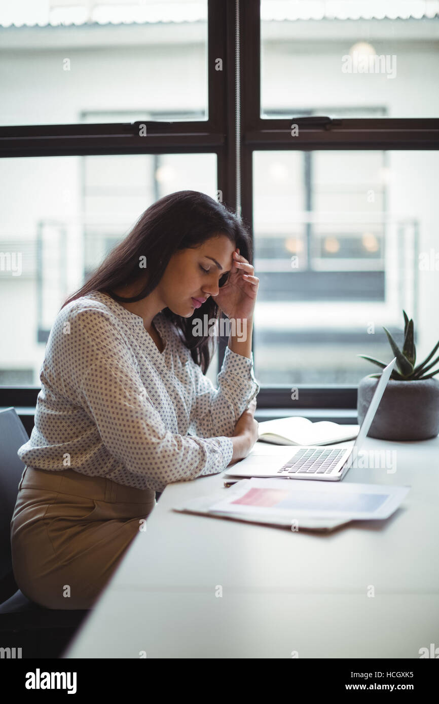 Stressed businesswoman sitting at his desk Stock Photo