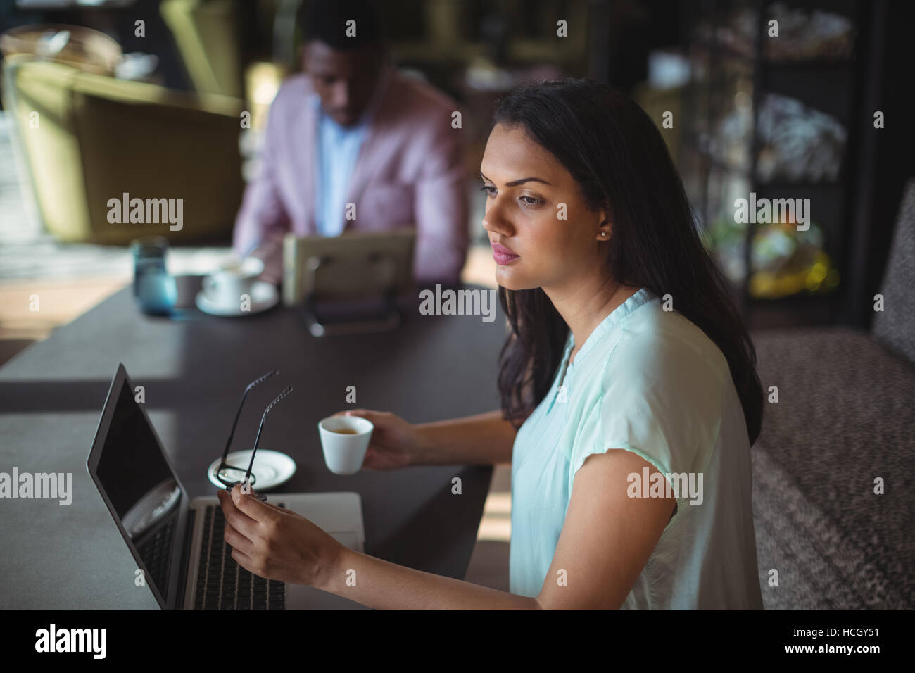 Thoughtful businesswoman holding coffee cup sitting at her desk Stock Photo
