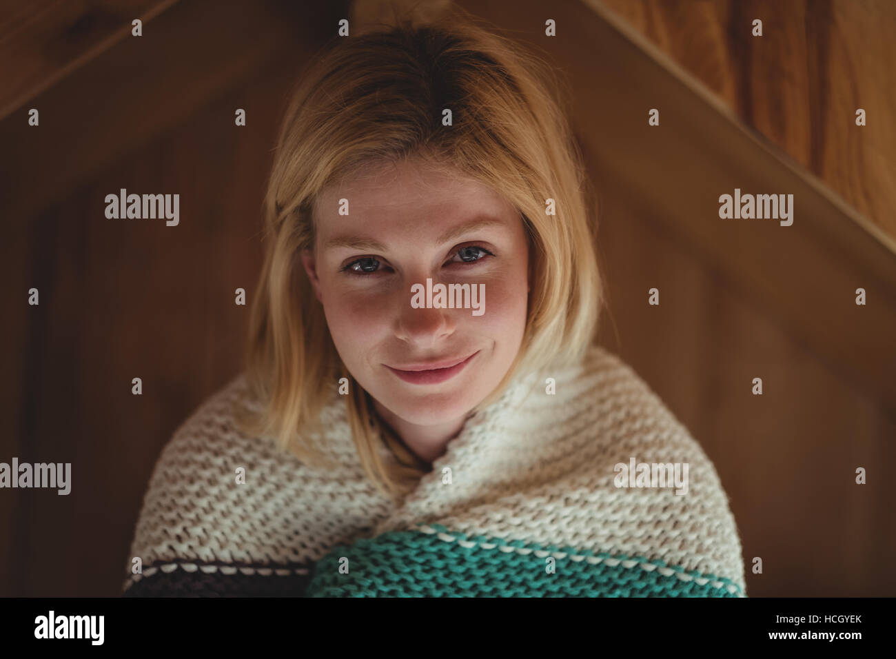 Portrait of beautiful woman wrapped in woolen blanket in bedroom Stock Photo