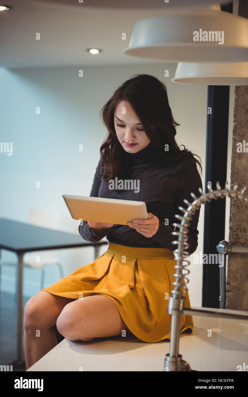 Woman sitting on kitchen worktop using digital tablet Stock Photo