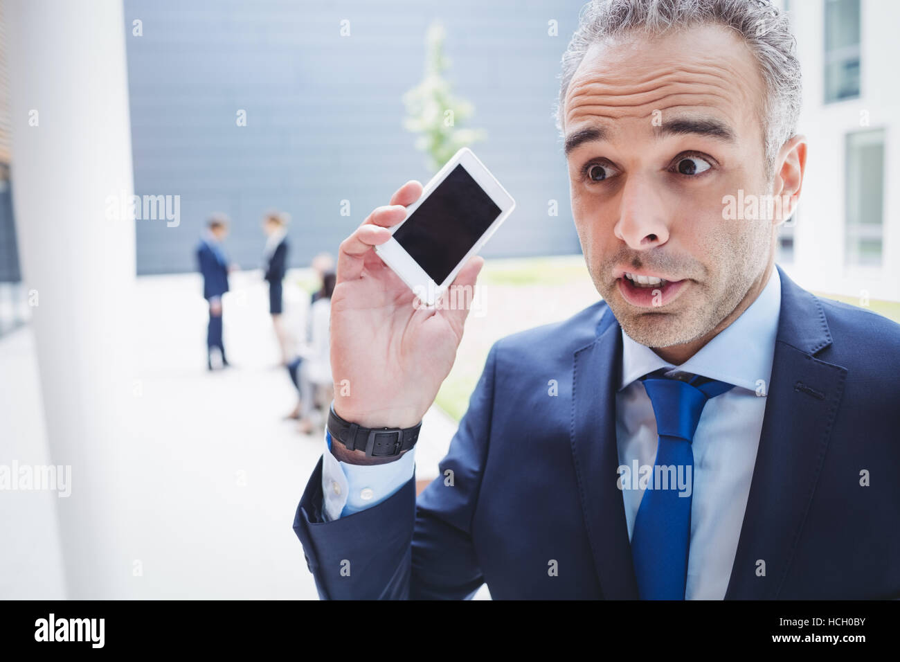 Businessman holding mobile phone and frowning Stock Photo