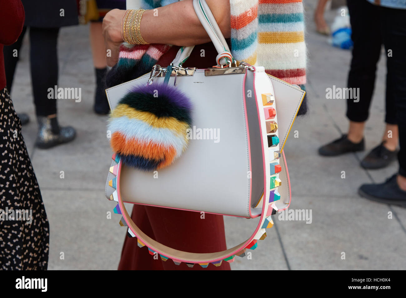 Woman with white leather bag with colorful fur accessory before Cristiano Burani fashion show, Milan Fashion Week street style. Stock Photo