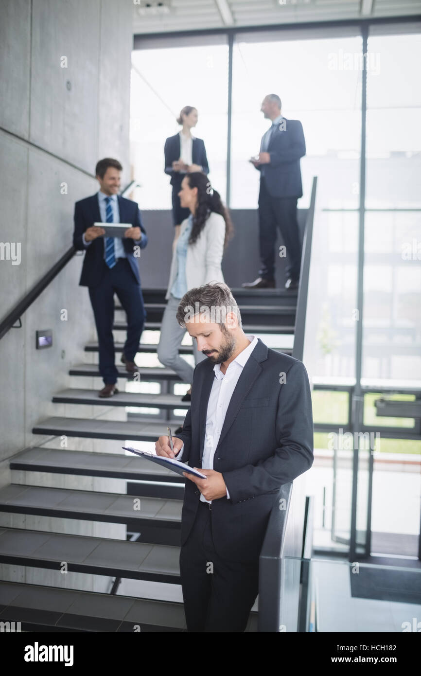 Businessman writing on clipboard Stock Photo - Alamy