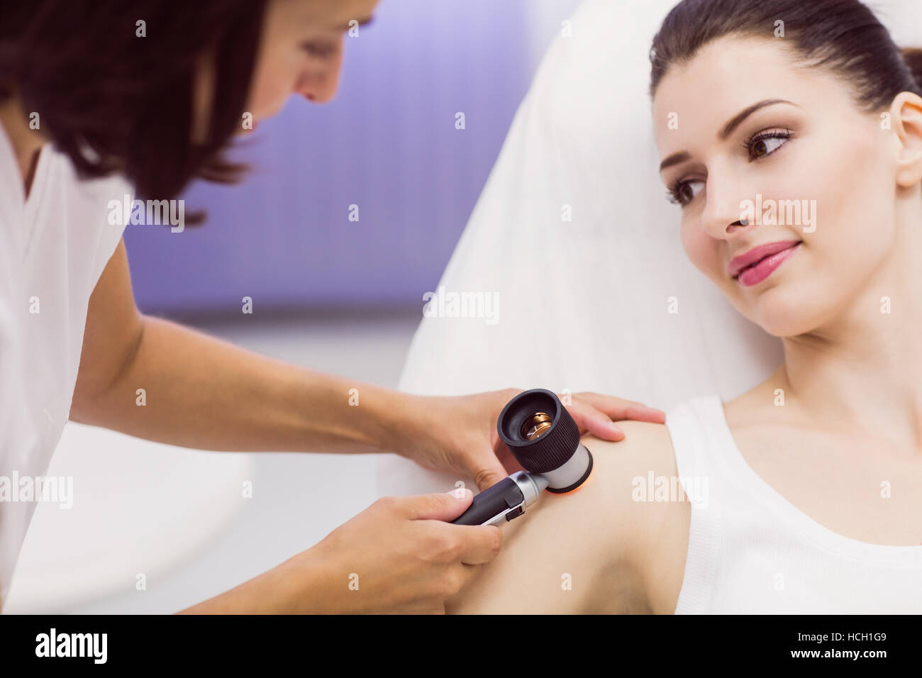 Dermatologist examining skin of patient with dermatoscope Stock Photo