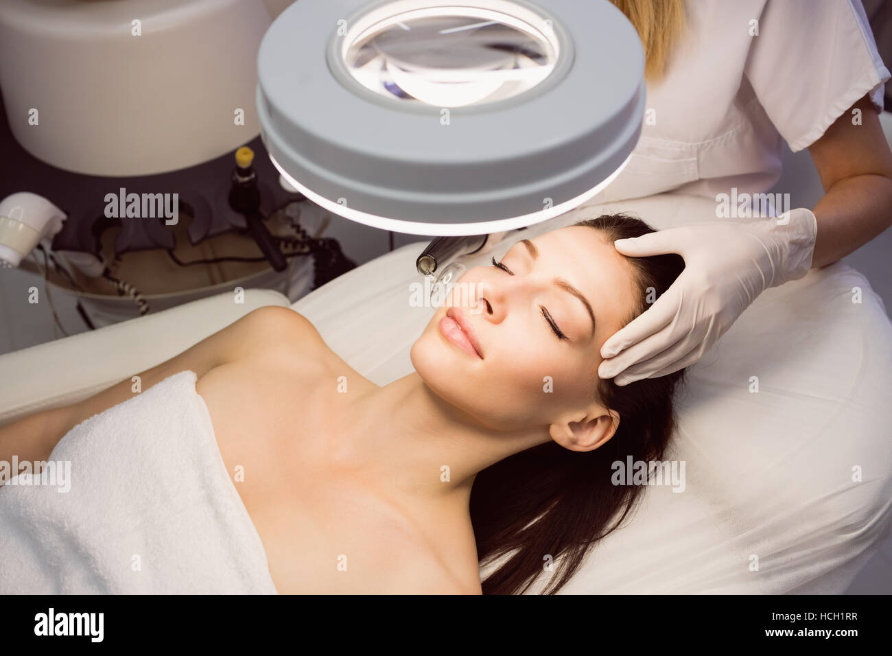 Dermatologist performing laser hair removal on patient face Stock Photo