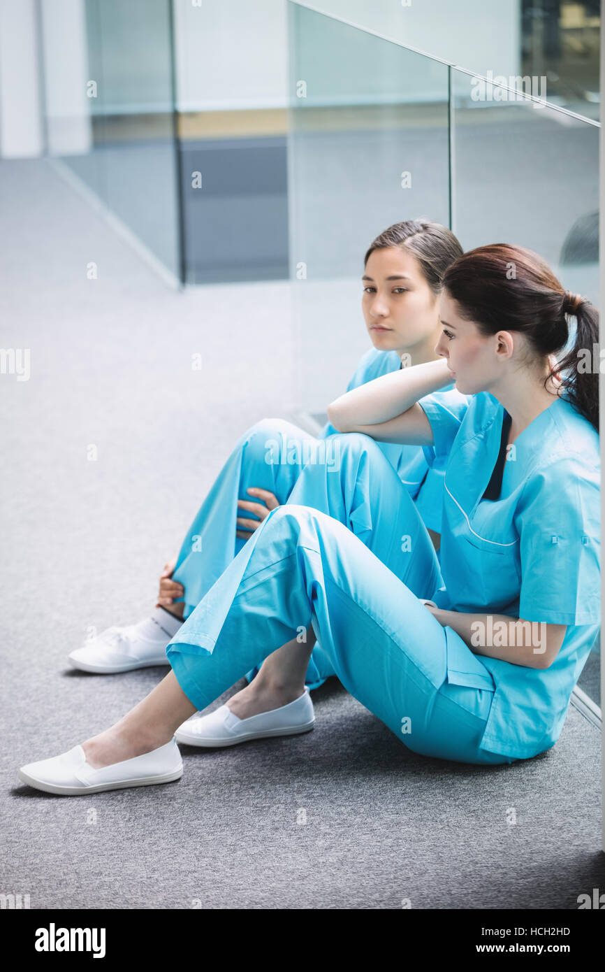 Sad nurses sitting on corridor Stock Photo