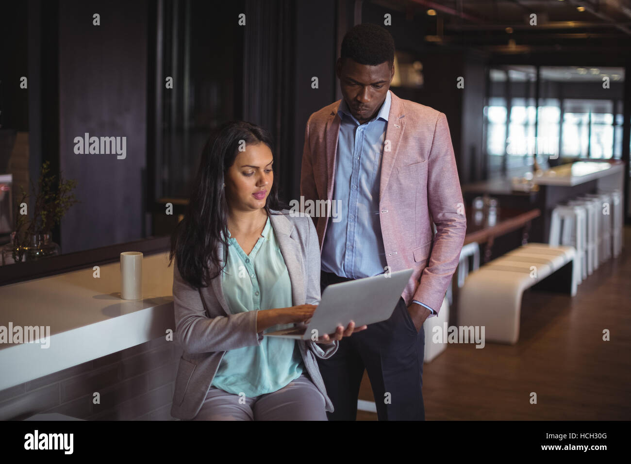 Businessman and a colleague discussing over laptop Stock Photo