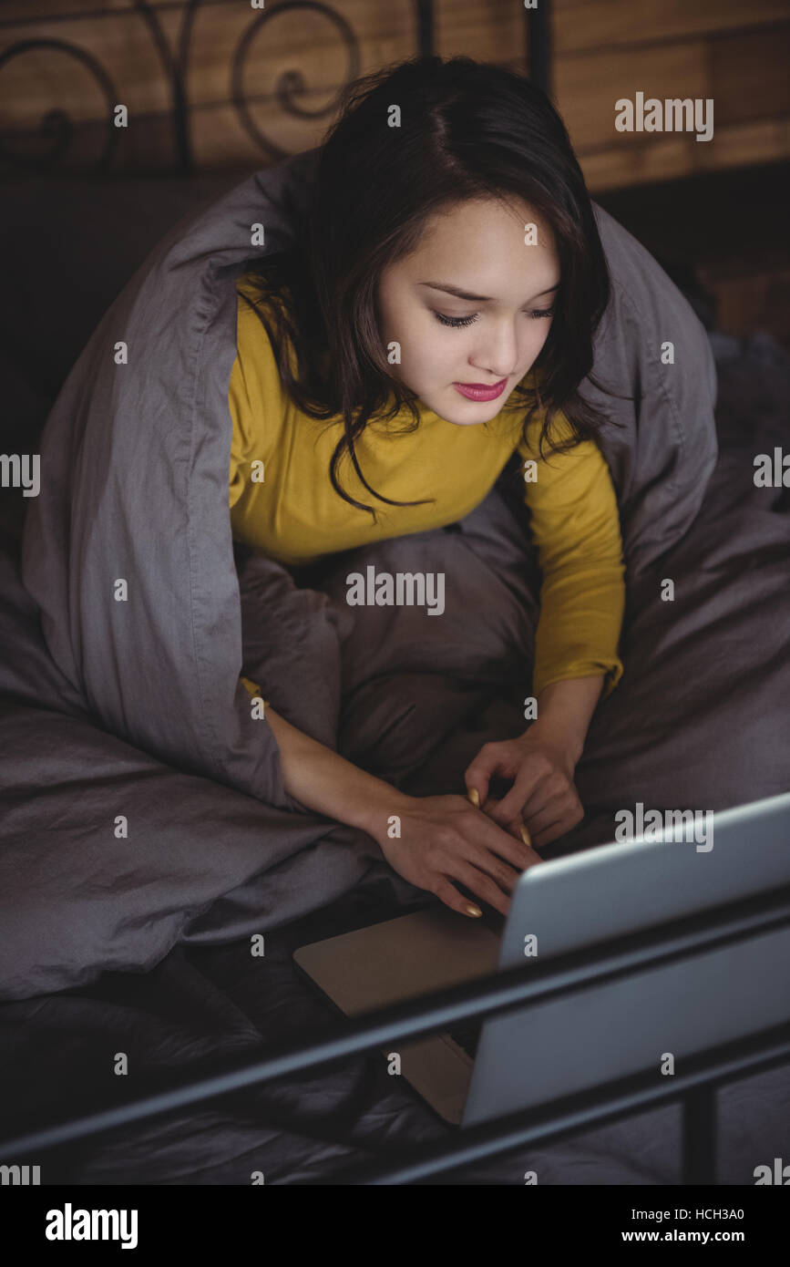 Woman lying on bed using laptop in bedroom Stock Photo Alamy