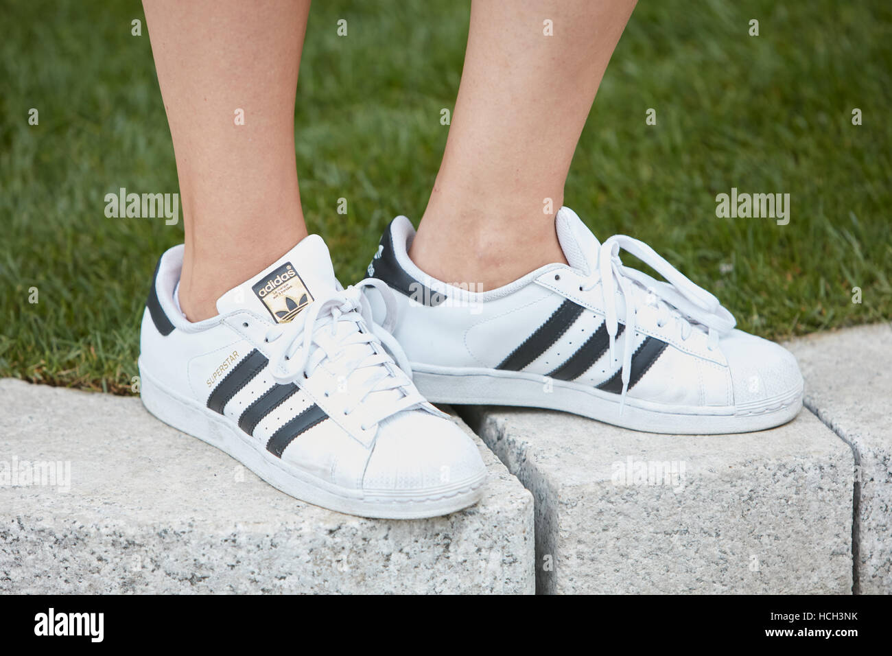 Woman with white Adidas superstar sneakers before Giorgio Armani fashion show, Milan Fashion Week street style on September 23. Stock Photo