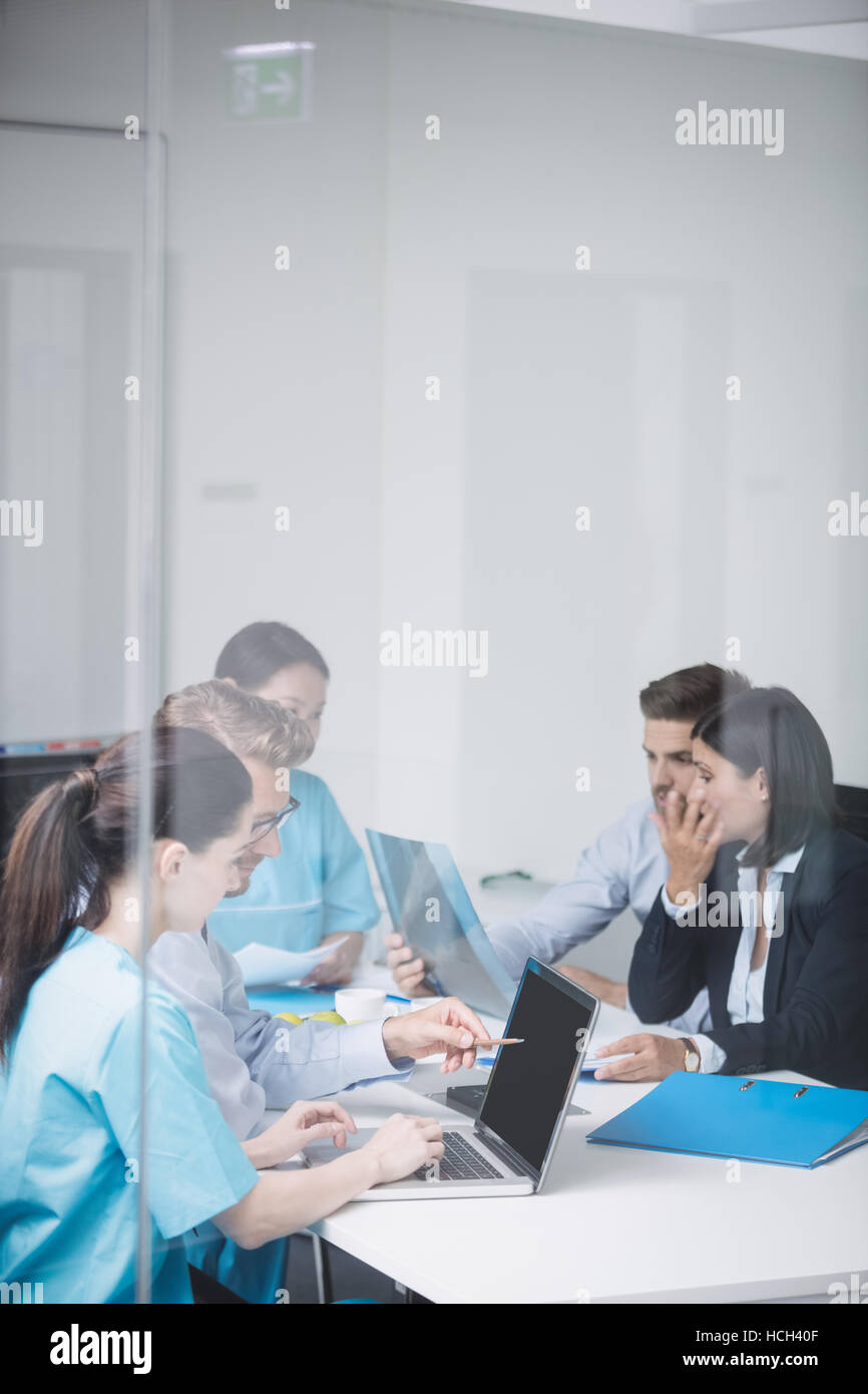 Doctors discussing over laptop in meeting Stock Photo