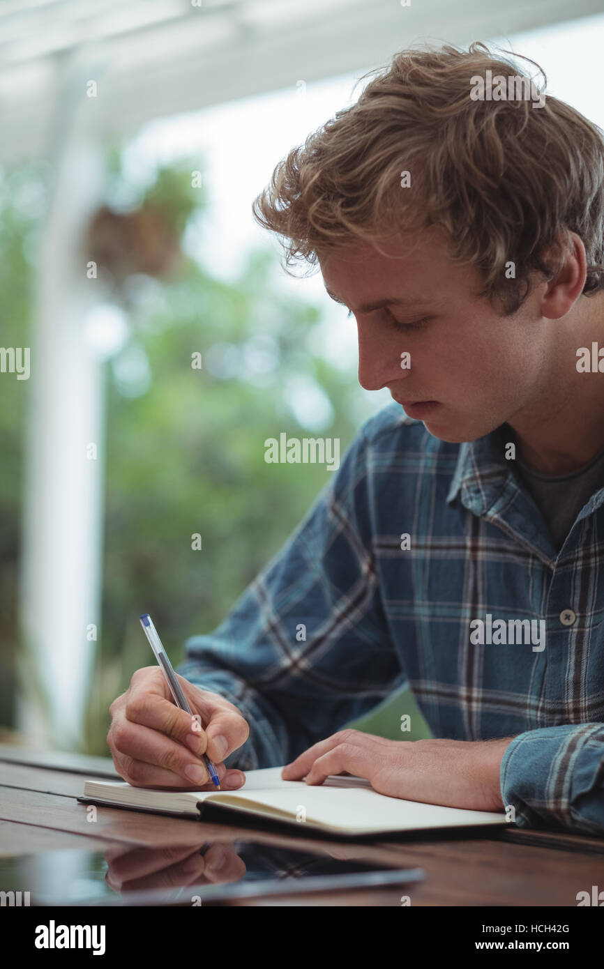 Man sitting at desk writing on diary Stock Photo