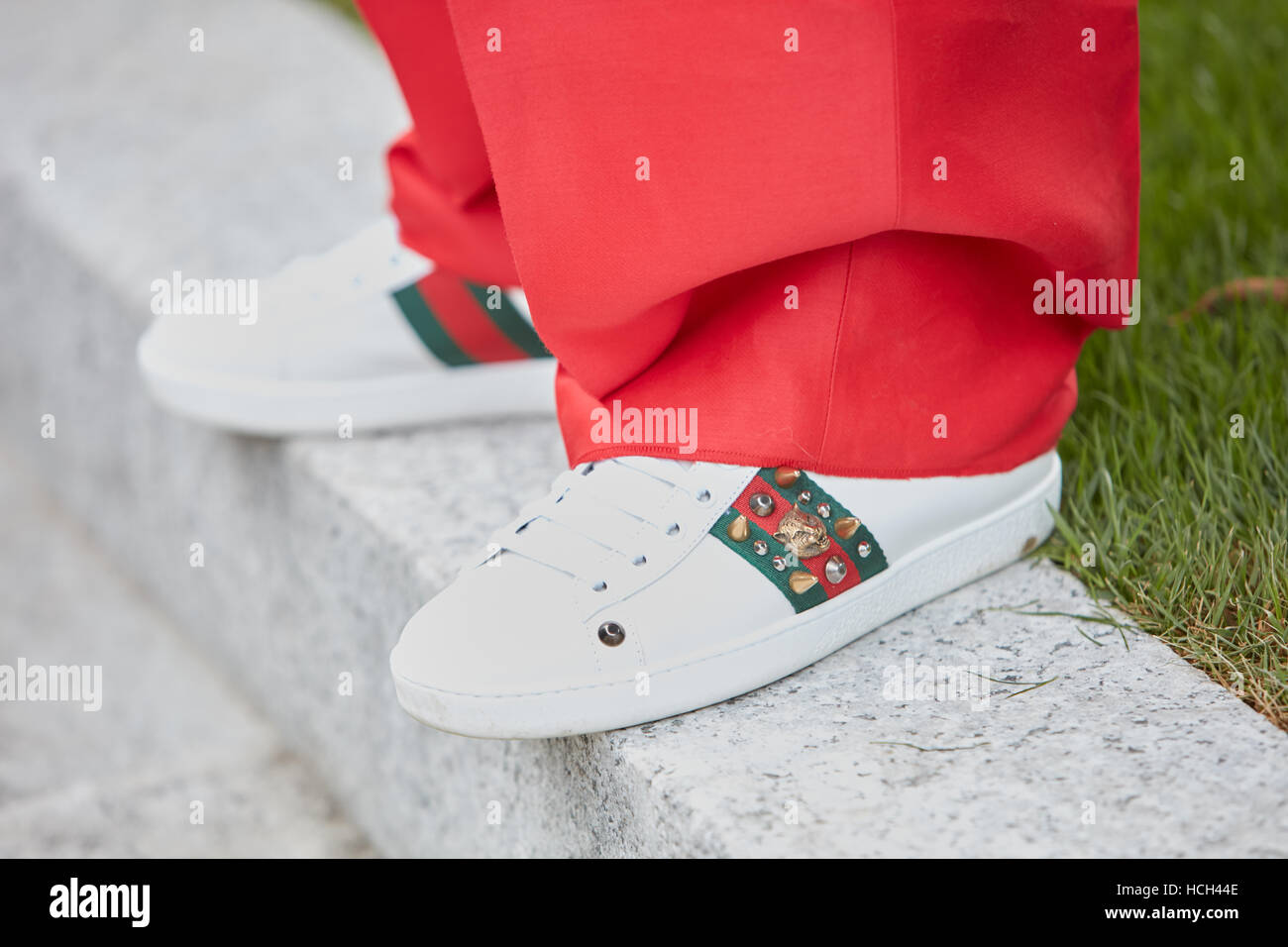 Woman with white Gucci sneakers and red trousers before Giorgio Armani fashion show, Milan Fashion Week street style in Milan. Stock Photo