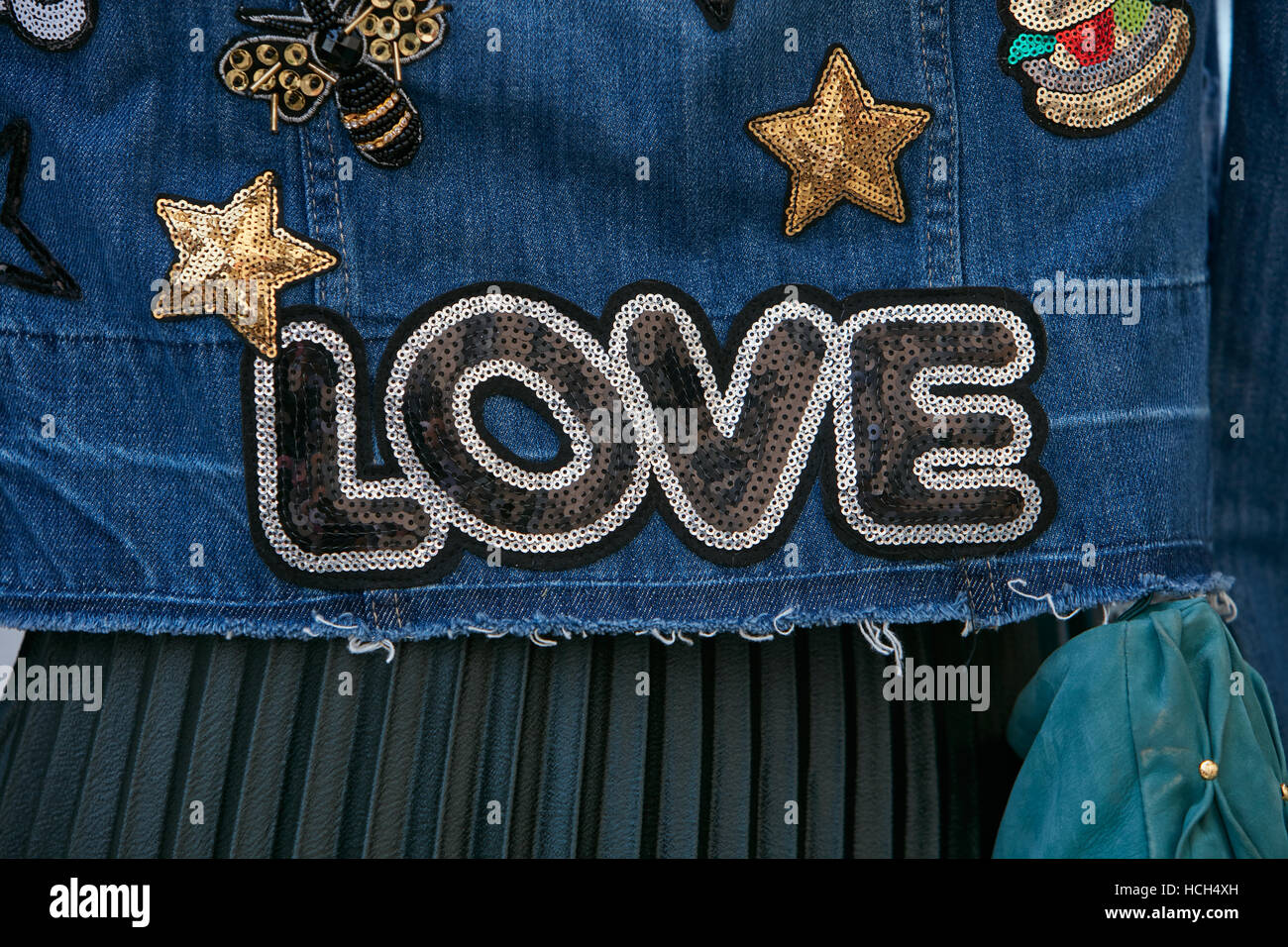 Woman with blue jeans jacket with Love sequin writing before Giamba fashion show, Milan Fashion Week street style on September. Stock Photo