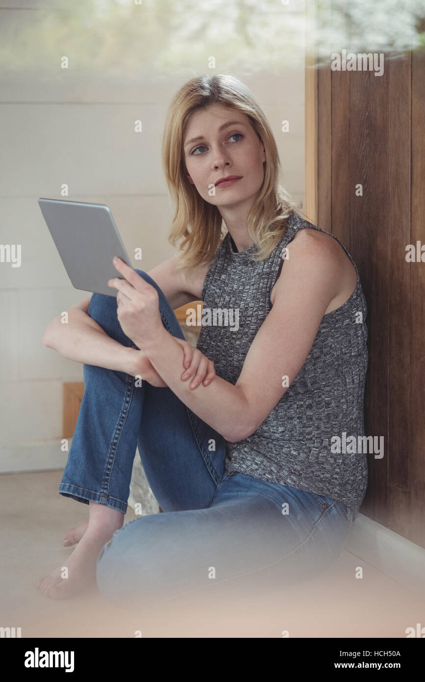 Thoughtful woman using digital tablet Stock Photo