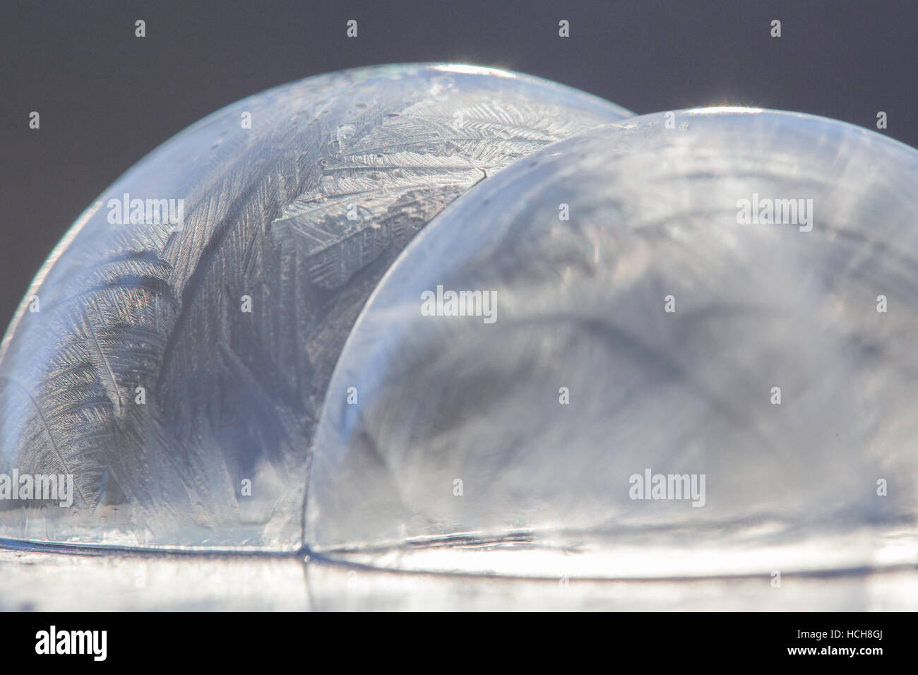 Two icy, frozen soap bubble domes connected in the middle in bright light Stock Photo