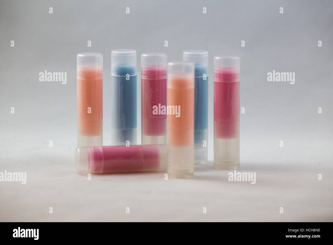 Arrangement of many clear chapstick shaped tubes with orange, blue, and red contents on a white background Stock Photo