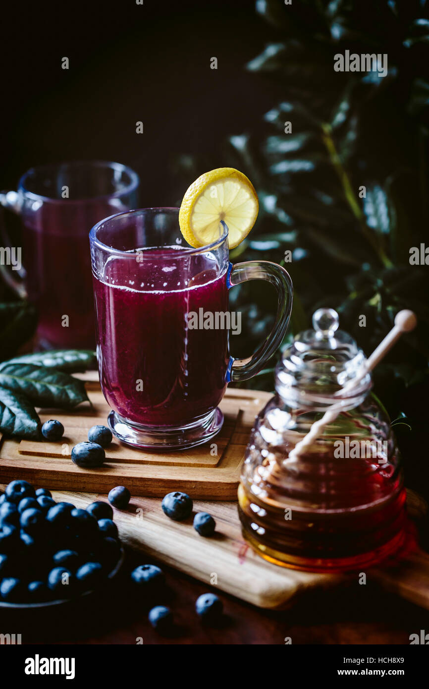 A glass of blueberry hot toddy garnished with a lemon slice is photographed from the front view. Stock Photo