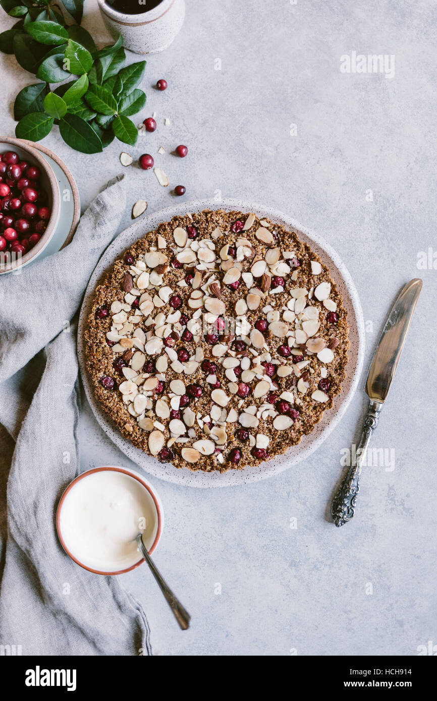 A cranberry almond tart is photographed along with creme fraiche and fresh cranberries from the top view. Stock Photo
