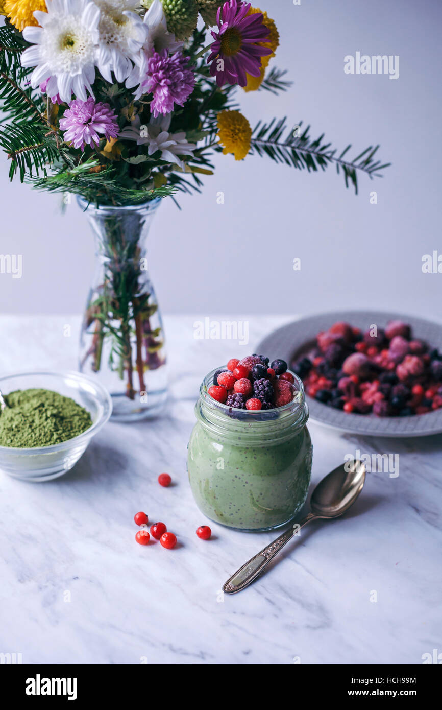 Matcha green tea chia pudding topped with frozen berries in a glass jar Stock Photo