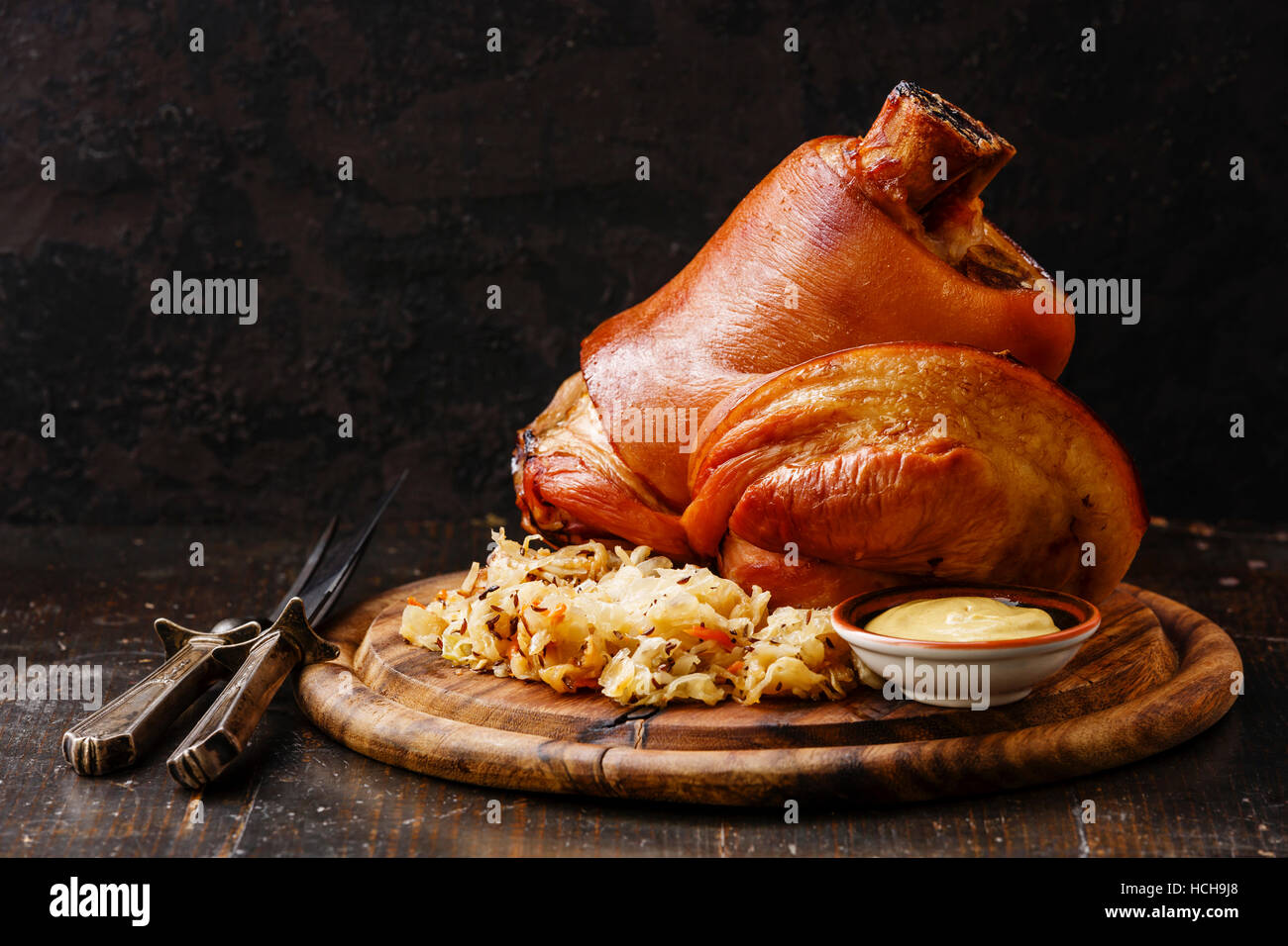 Roasted pork knuckle eisbein with braised boiled cabbage and mustard on wooden cutting board Stock Photo