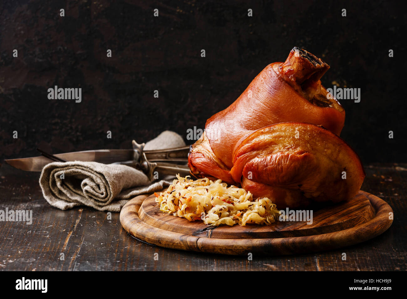 Roasted pork knuckle eisbein with braised boiled cabbage on wooden cutting board Stock Photo