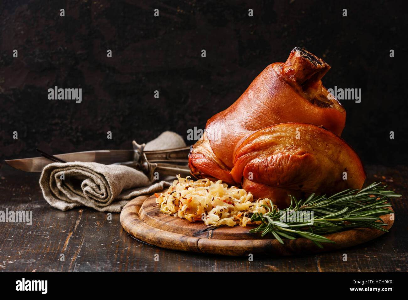 Roasted pork knuckle eisbein with braised boiled cabbage and rosemary on wooden cutting board Stock Photo