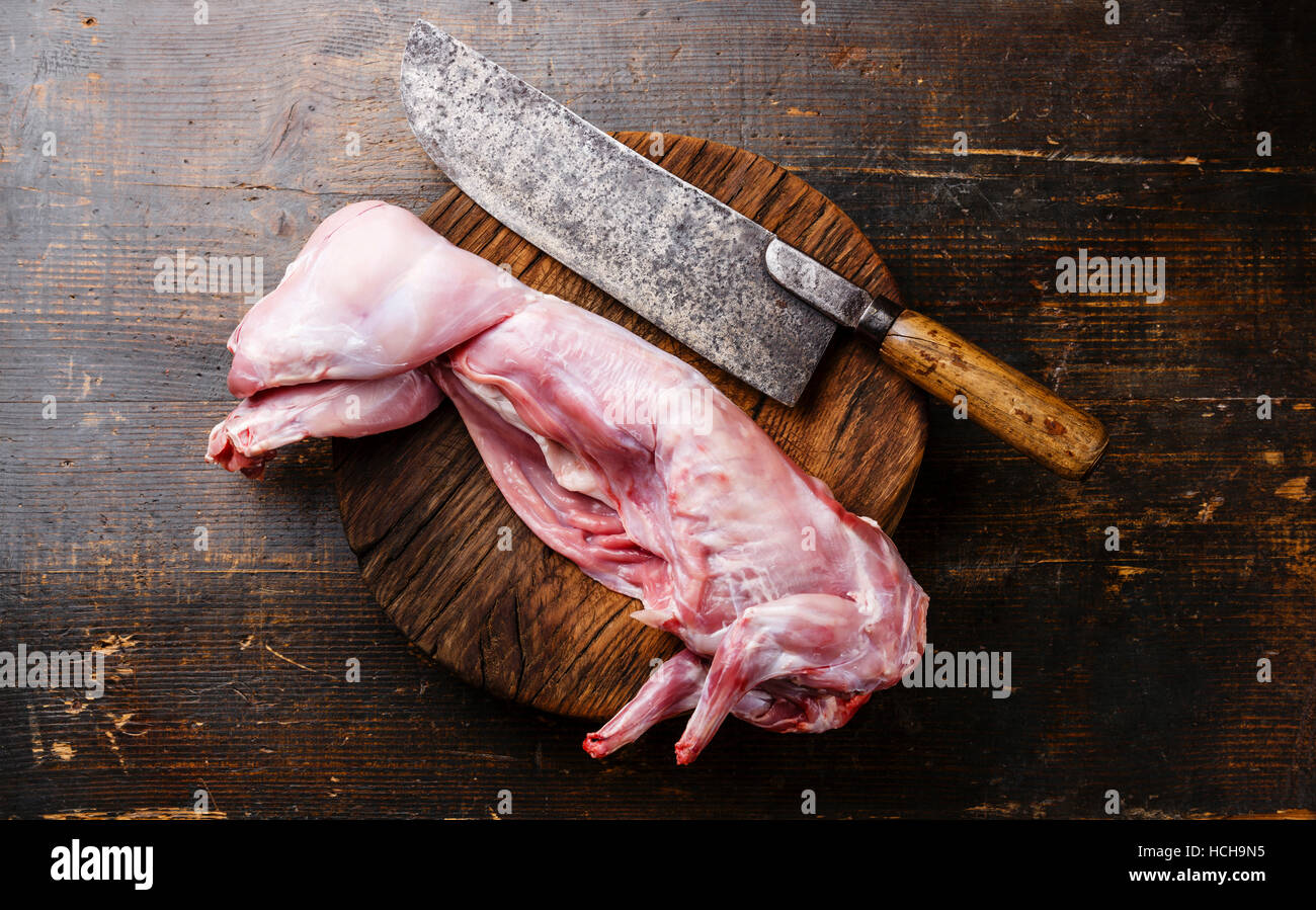 Raw fresh whole rabbit bird cut and meat cleaver on dark wooden background Stock Photo