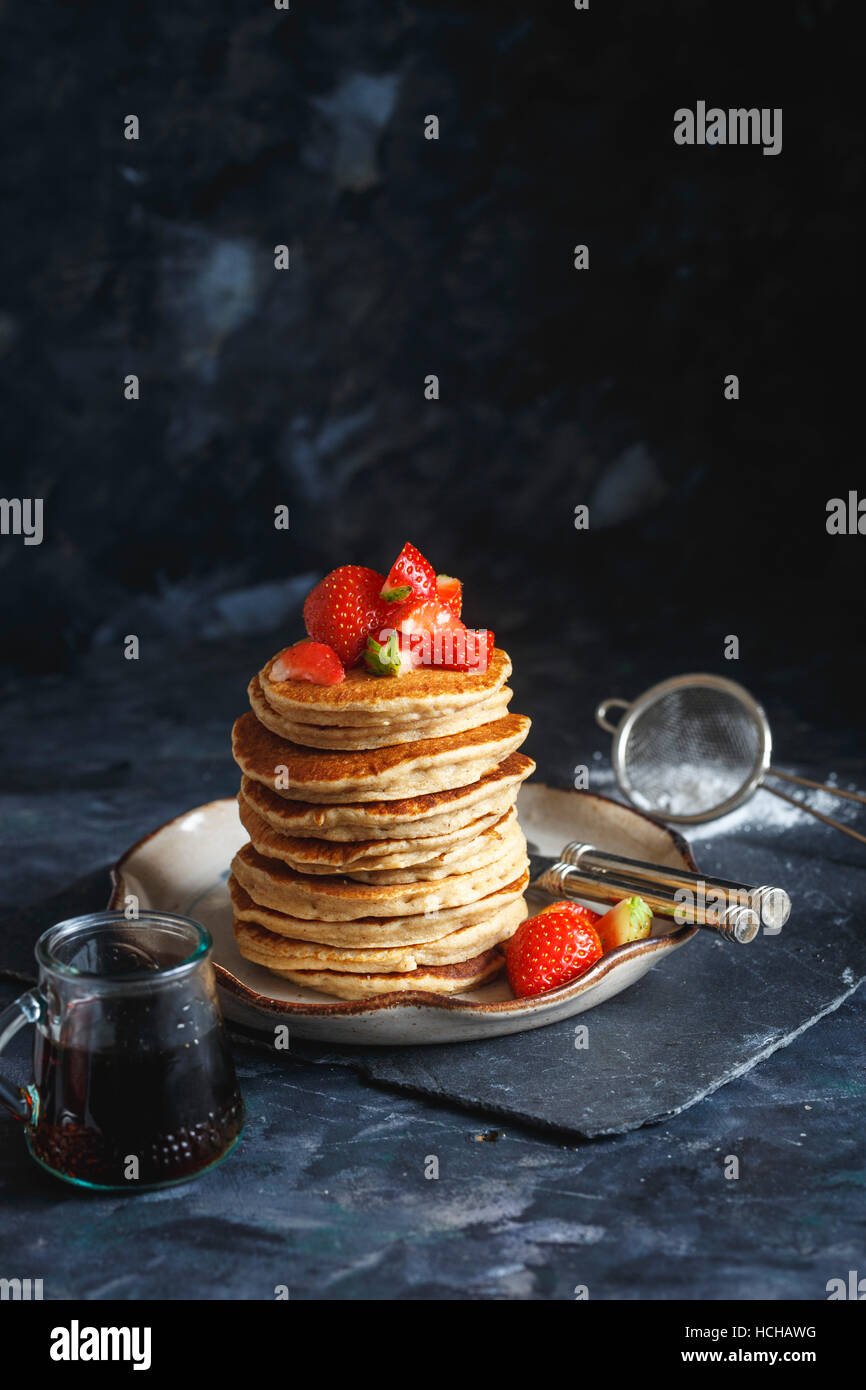 Stack of Gluten free Oat Flour Pancakes served with chopped Strawberries and Maple Syrup Stock Photo
