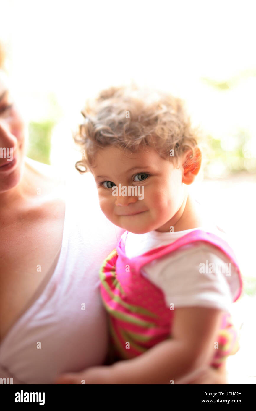Girl, age 9 months, in her mother's arms during a bright early Spring afternoon. Stock Photo