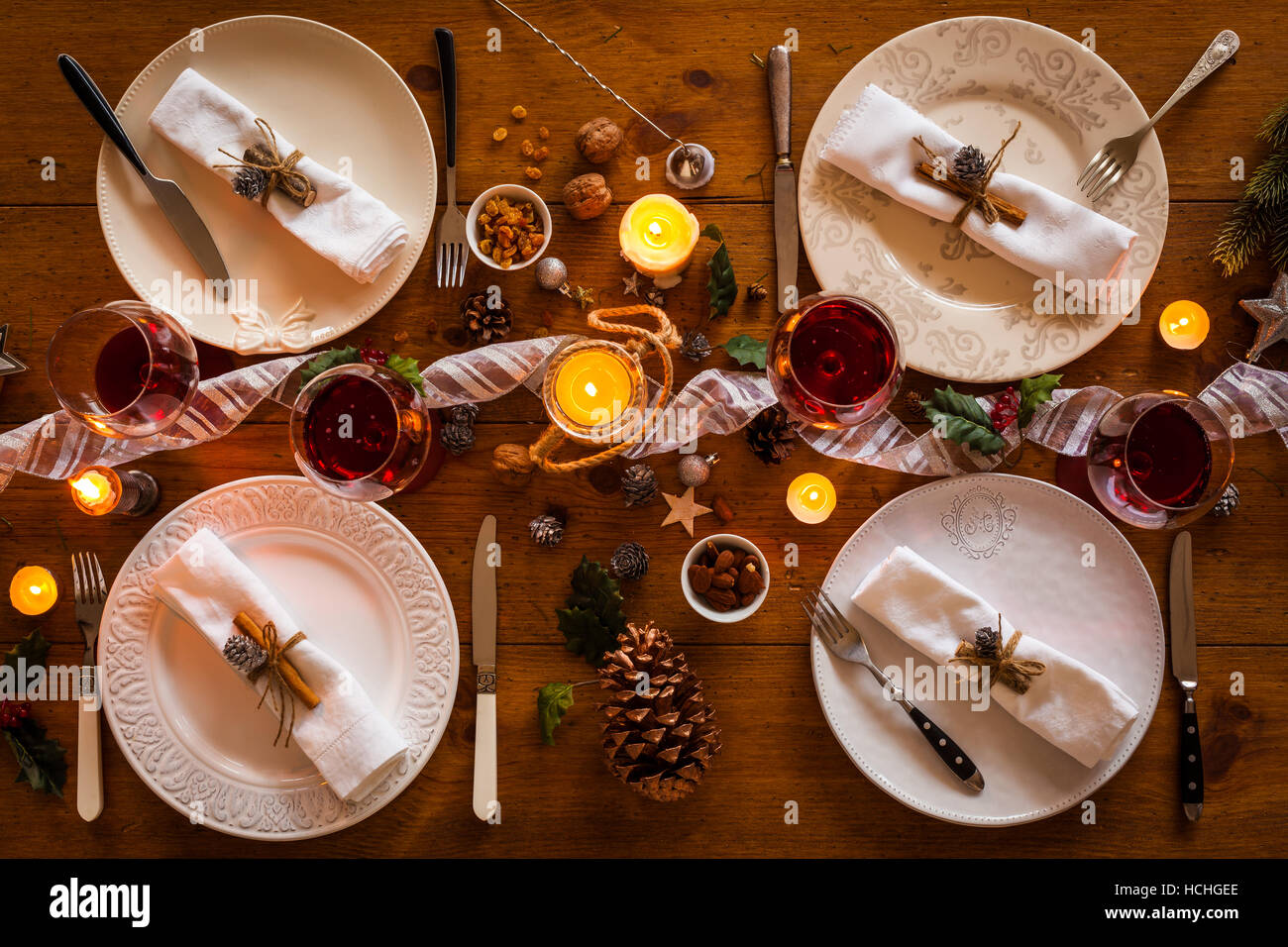 Christmas table setting for family dinner at a cosy rustic table with candles and decorations. Top view. Stock Photo