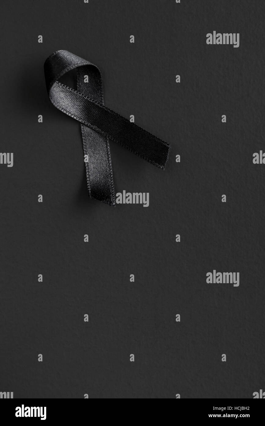 Black satin ribbon on black background. R.I.P. symbol. Stock Photo