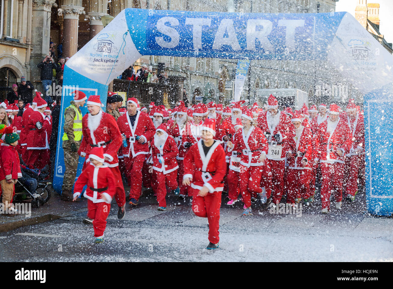 A crowd of people dressed as Santa Claus starting a charity race, Winchester, Hampshire, England, UK Stock Photo
