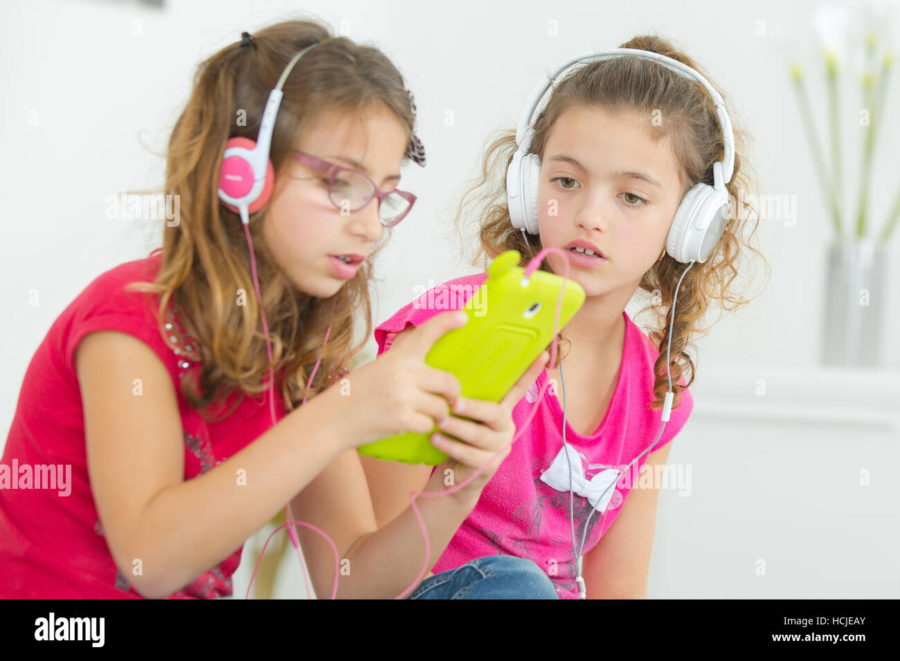 Two children wearing headphones, holding electronic device Stock Photo Alamy