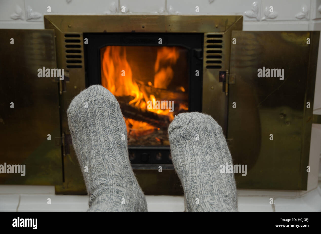 Feet with gray socks in front of an indoors fireplace Stock Photo