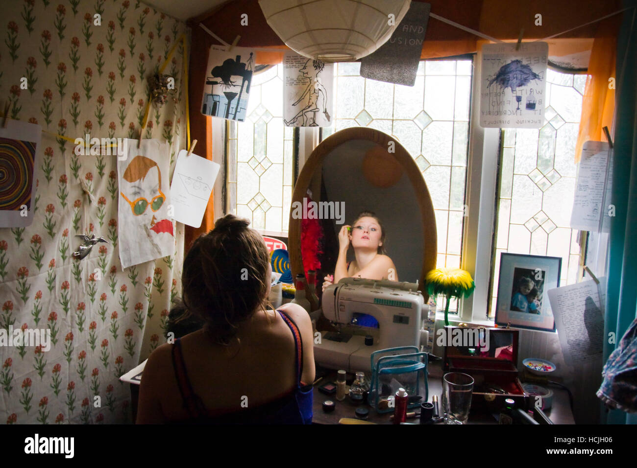 A young woman puts on makeup in her room at home in Seattle, Washington. Stock Photo