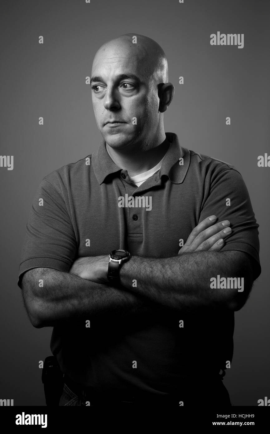 A male veteran looks off to his right with his arms crossed in front of his body. Stock Photo