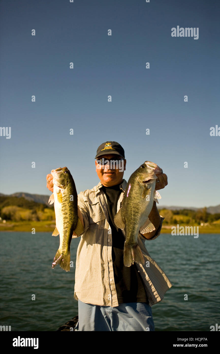 A man holds up his catch proudly for the camera while bass fishing in Lake Casitas Stock Photo