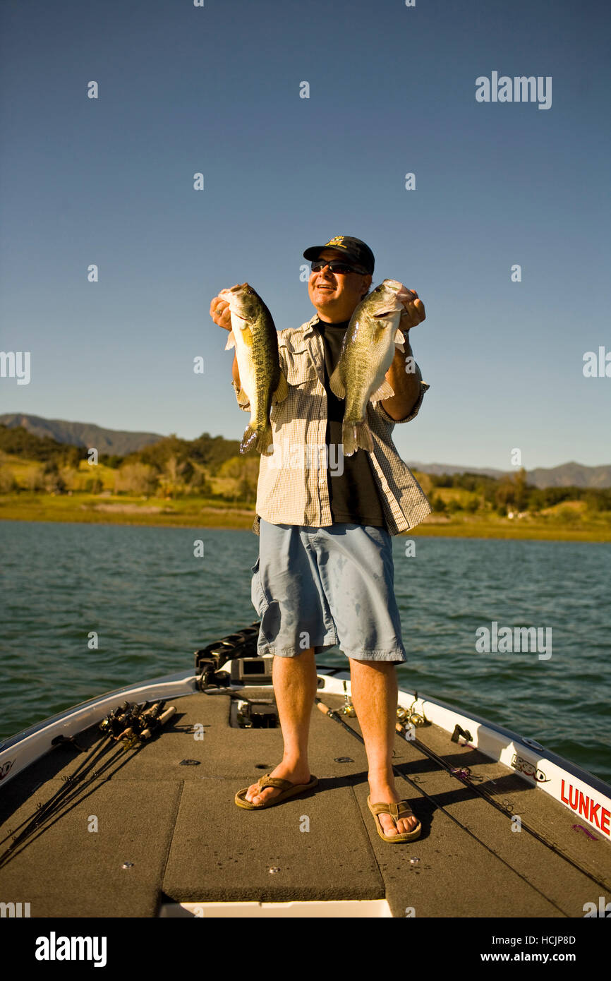 A man holds up his catch proudly for the camera while bass fishing in Lake Casitas Stock Photo