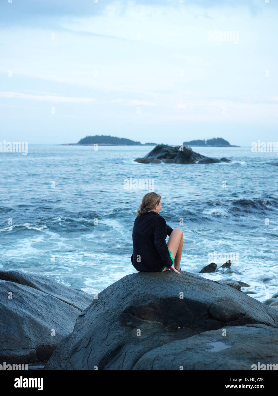a girl sits on a rock and looks out to sea Stock Photo - Alamy
