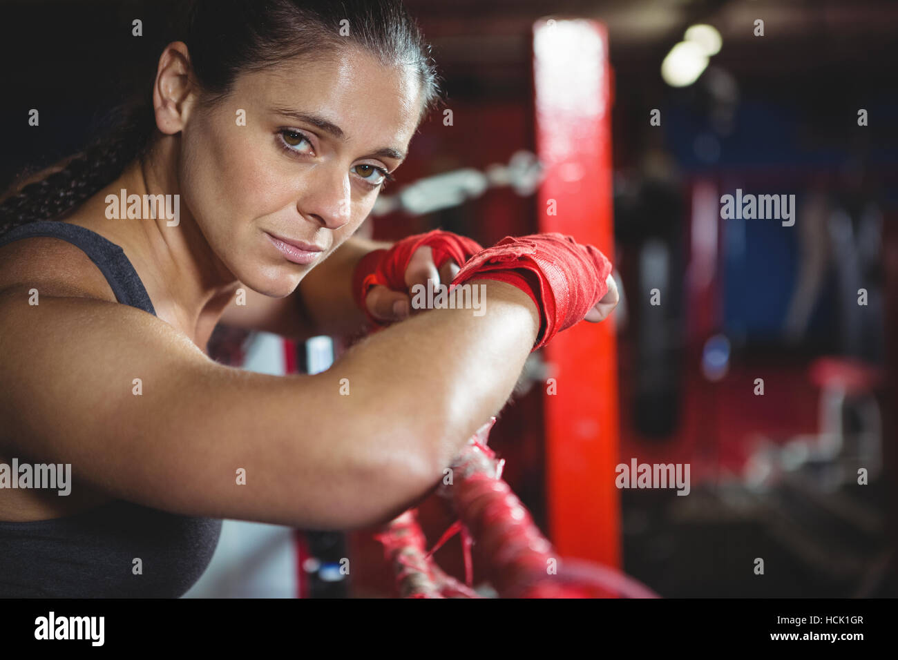 Confident female boxer leaning on boxing ring Stock Photo