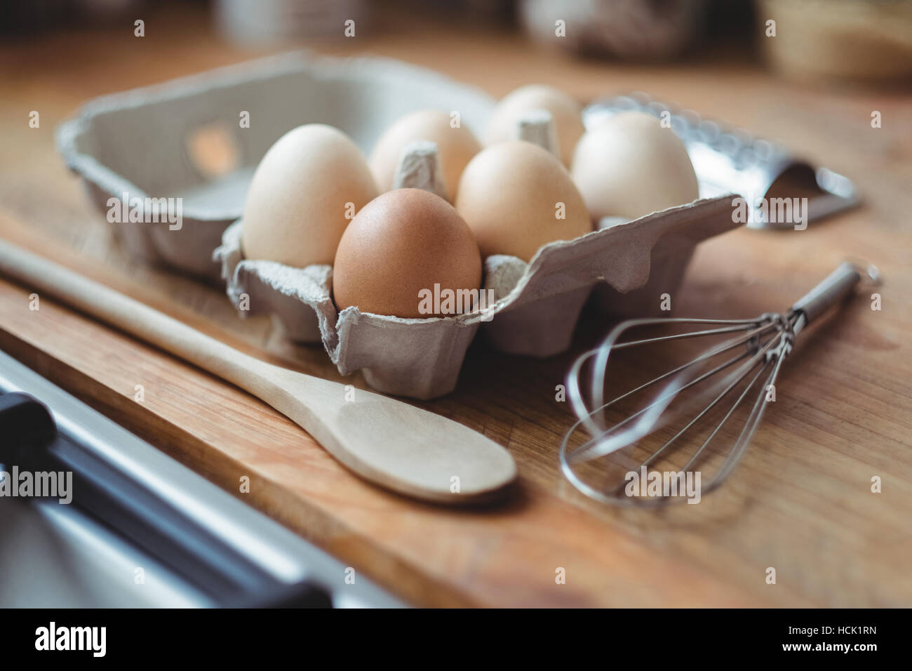 Eggs, whisker and wooden spoon on table Stock Photo