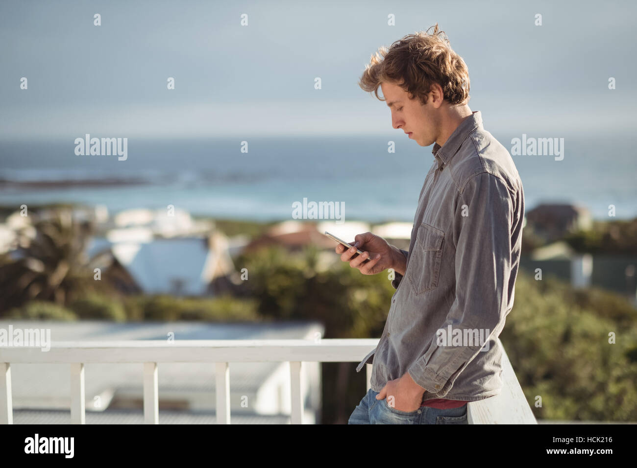 Man standing on balcony and using mobile phone Stock Photo