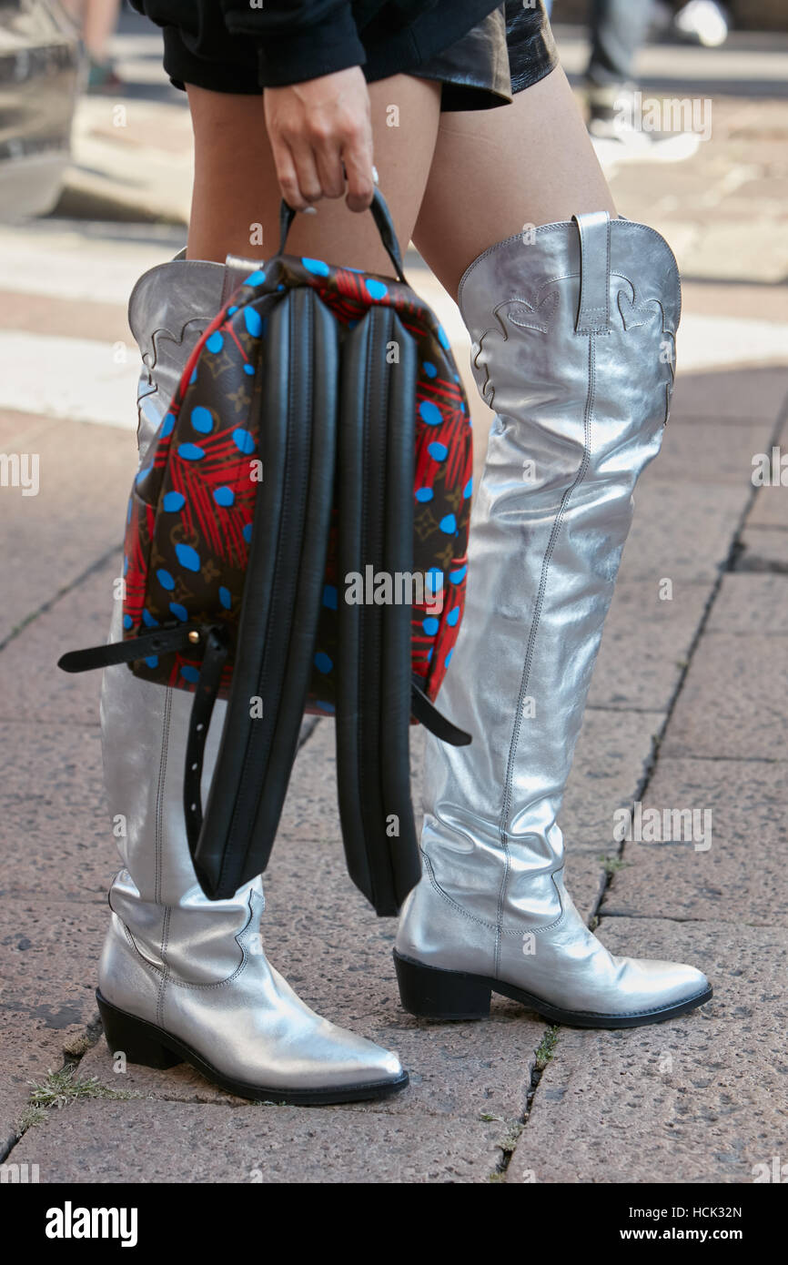Woman with high silver boots and Louis Vuitton backpack before