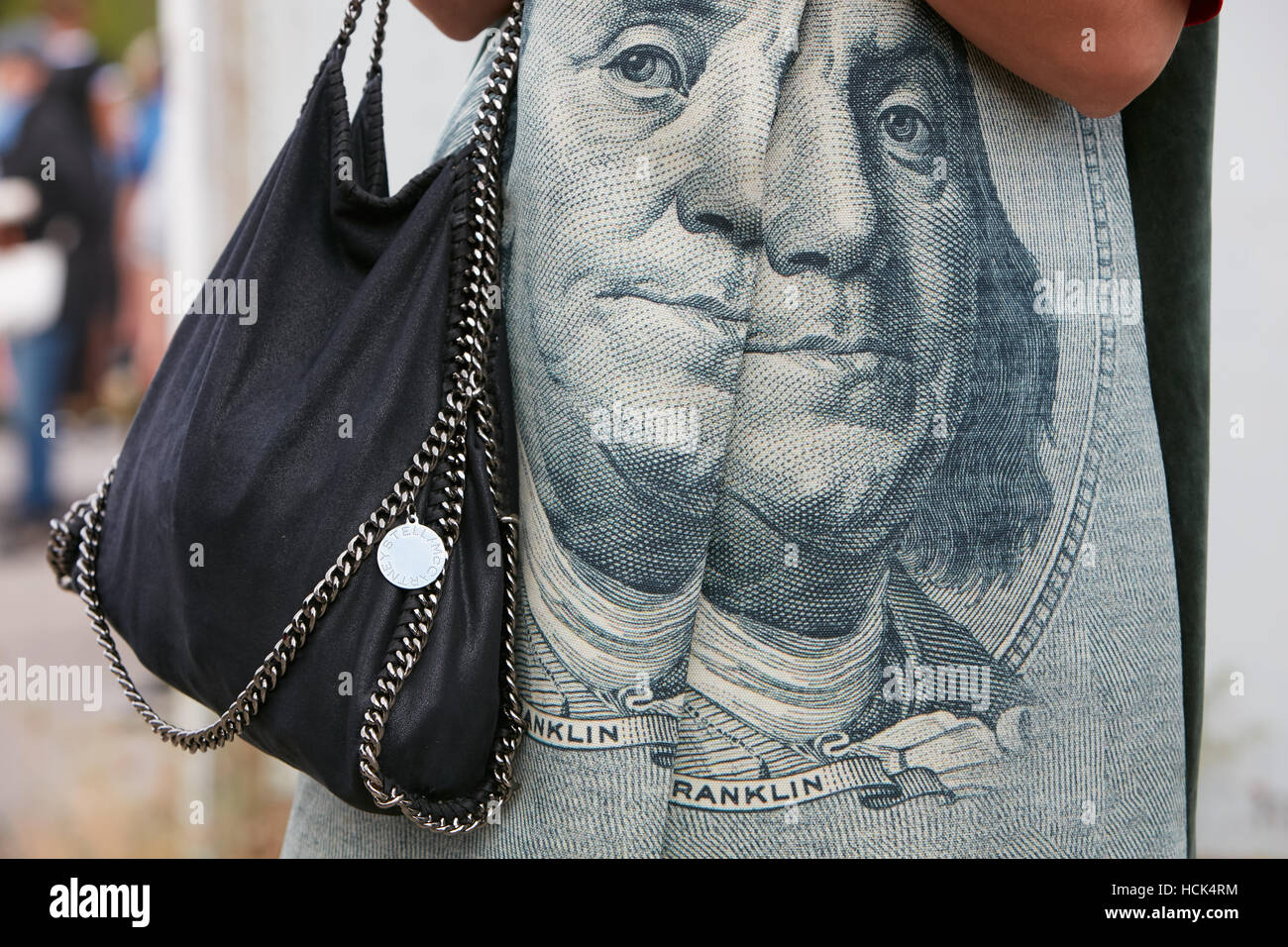 Woman with Stella McCartney leather bag and Franklin dollar face on jacket before Gucci fashion show, Milan Fashion Week street. Stock Photo