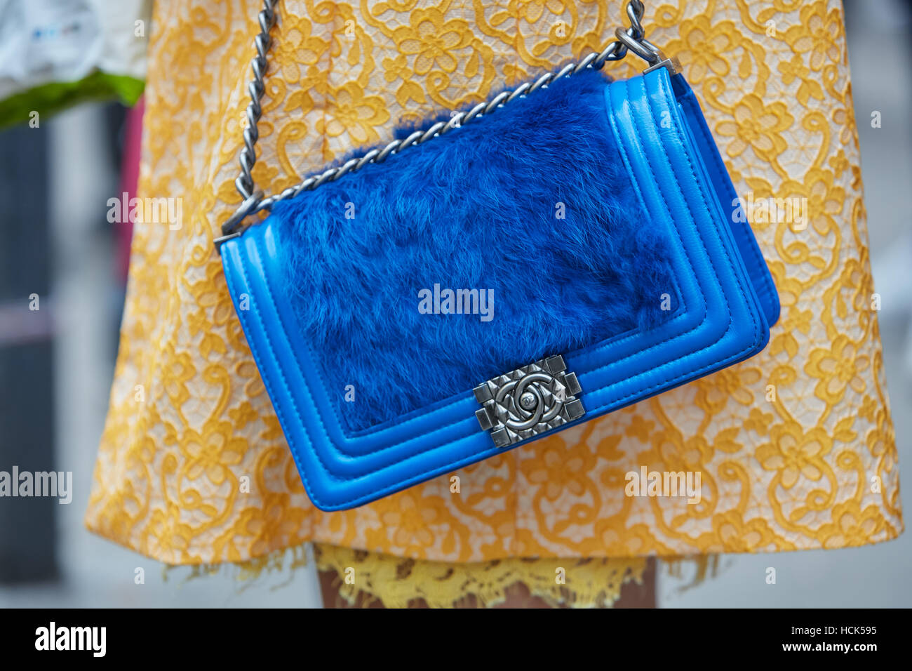 Woman with blue Chanel bag with fur and yellow floral coat before Gucci  fashion show, Milan Fashion Week street style Stock Photo - Alamy