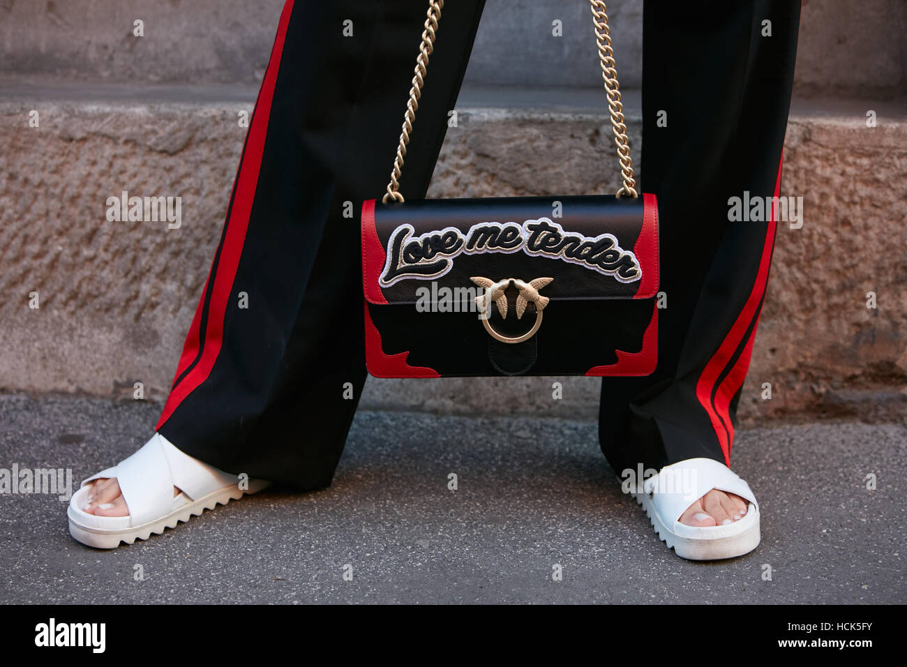 Woman with Love me tender Pinko black and red bag before Prada fashion show, Milan Fashion Week street style on September 22 Stock Photo