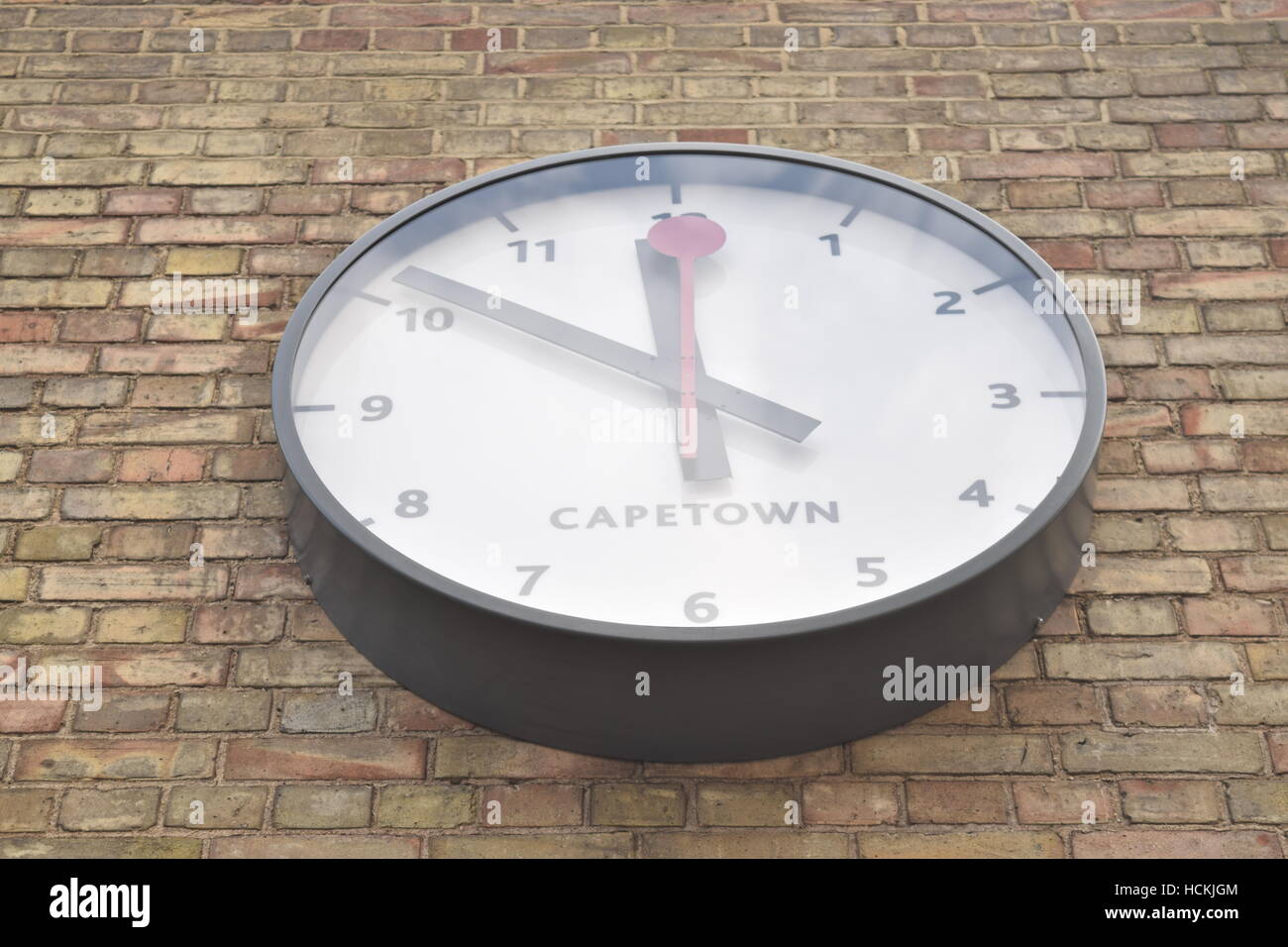 Large white and black clock on a brick wall showing the time in Cape