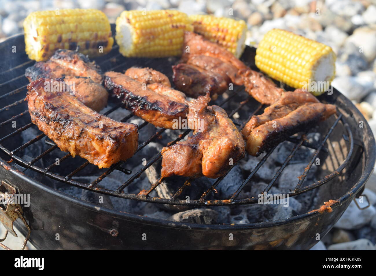Cooked crispy ribs with organic sweetcorn on a barbecue at the beach ...