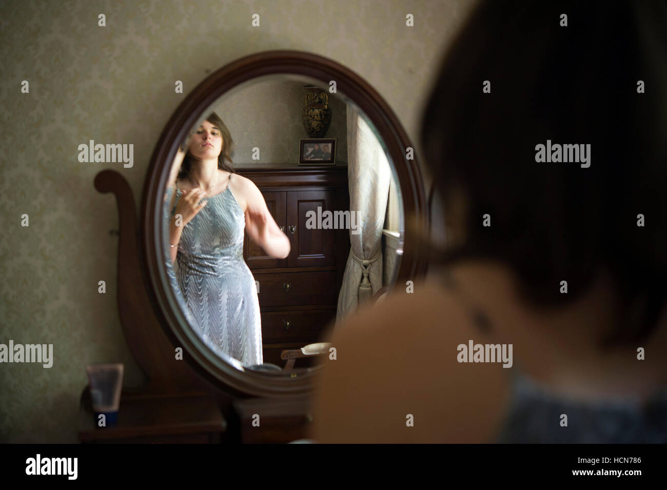 Young woman dressing in front of a vanity mirror Stock Photo