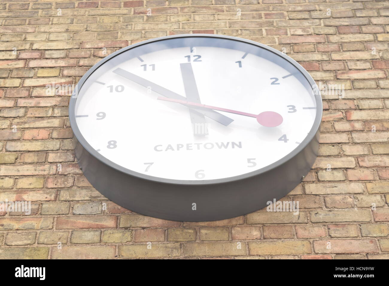 Large clock showing time from Cape Town on a brick wall; view from